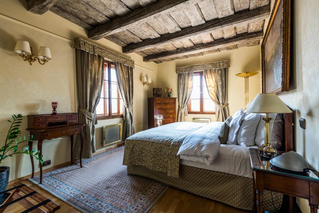 布拉格黄金井酒店的卧室配有床、桌子和窗户。