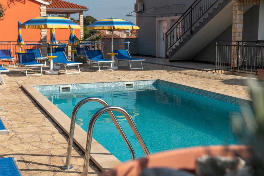 特罗吉尔Apartmani Grga的一个带蓝色椅子和遮阳伞的游泳池