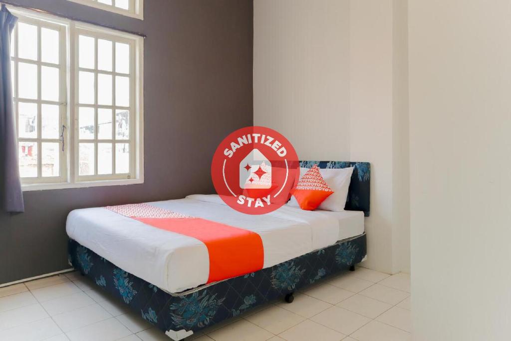 雅加达OYO 1111 Pasar Baru Inn的一间卧室,床上有红色标志