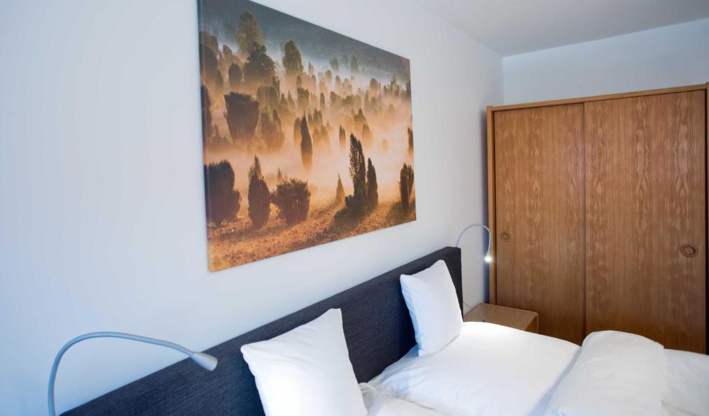 阿默灵豪森Landhaus Amelinghausen Ferienzimmer的卧室配有一张床,墙上挂有绘画作品