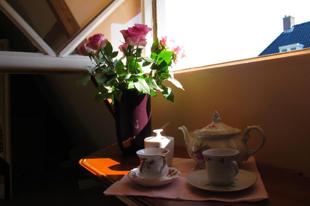 阿姆斯特丹野玫瑰酒店的一张桌子,上面放着花瓶和两个杯子