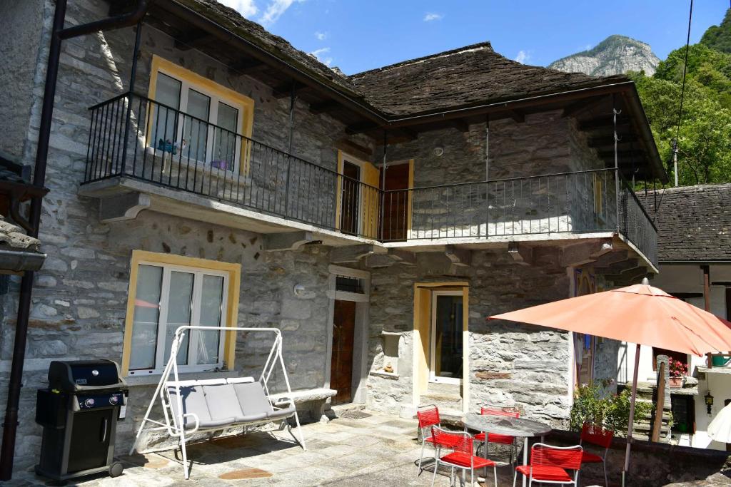 拉韦尔泰佐韦尔扎斯卡山谷鲁斯蒂科卢切萨度假屋的石头房子,配有桌椅和遮阳伞