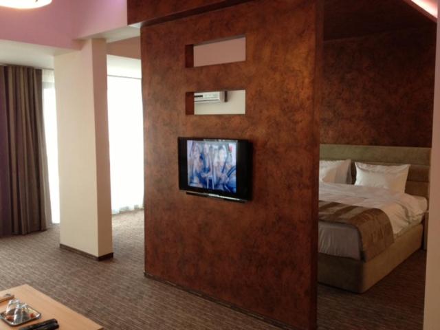 斯拉蒂纳CITY HOTEL & LOUNGE的一间酒店客房,配有一张床和一台墙上的电视