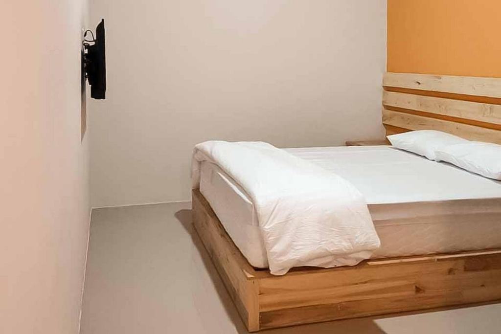 BaoenRedDoorz Syariah @ Haurgeulis的一间卧室配有一张带白色床单的木床