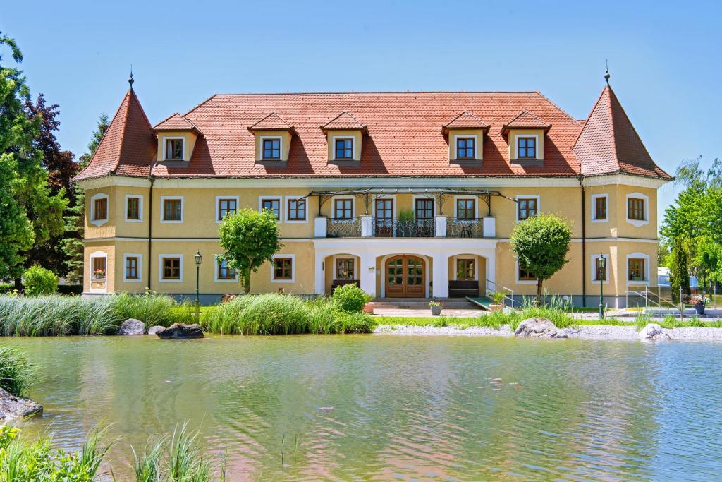 PettenbachAlmtalhotel Appartements in Pettenbach的一座黄色的大房子,前面有一个池塘