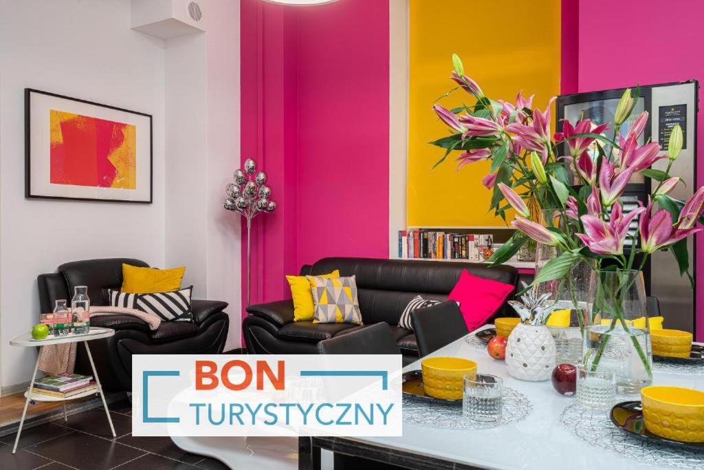 弗罗茨瓦夫Absynt Hostel Wrocław的客厅设有粉红色和黄色的墙壁和鲜花桌