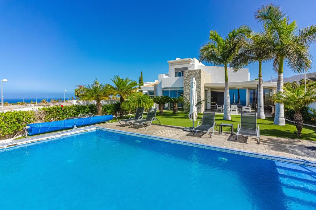 阿德耶Villa Eleonora, Luxury Villa with Heated Pool Ocean View in Adeje, Tenerife的棕榈树屋前的游泳池