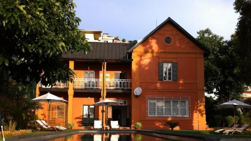 塔那那利佛曼德罗索庄园旅馆的一座大型橙色建筑,前面设有一个游泳池