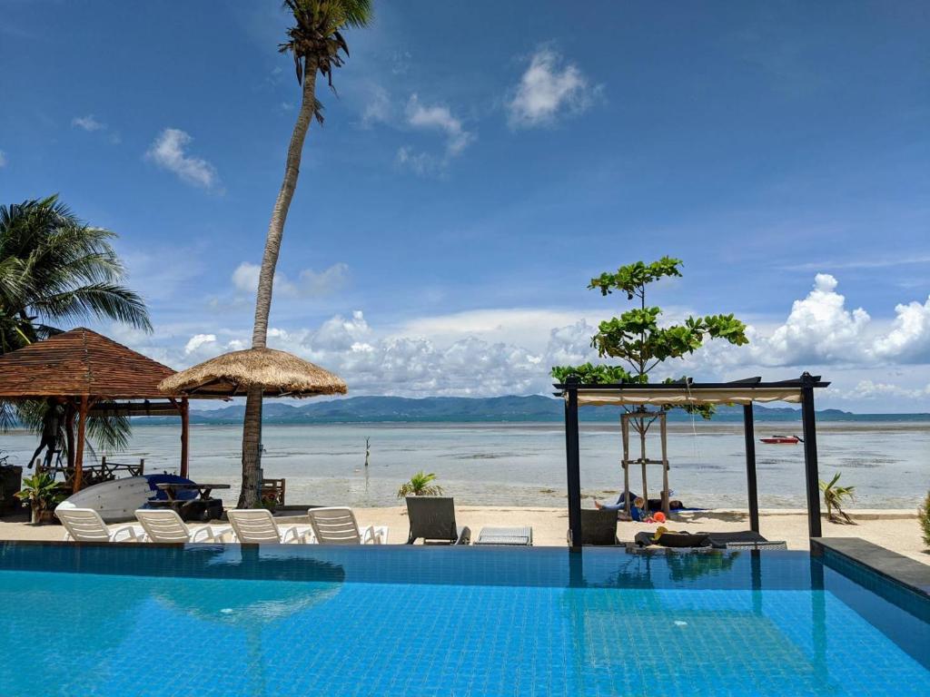 通萨拉Samutra Residences的海滩旁的游泳池,配有椅子和遮阳伞