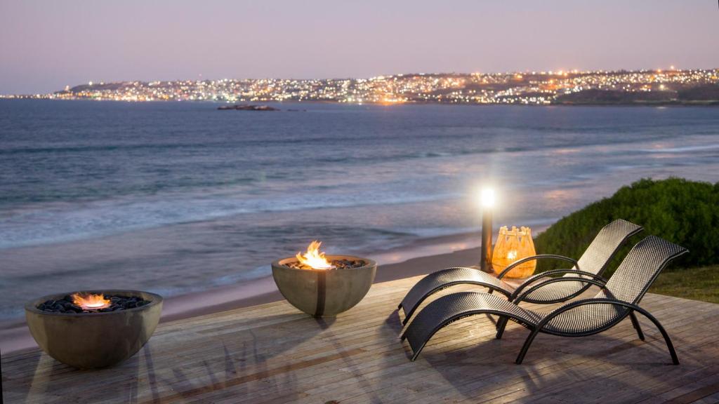 莫塞尔湾非洲海洋庄园酒店的海滩上晚上有两张火的桌子