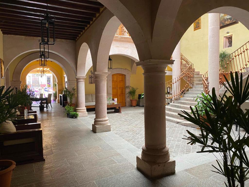 萨卡特卡斯Hotel Casa Faroles Centro Histórico的一座有柱子的建筑和种植了植物的走廊
