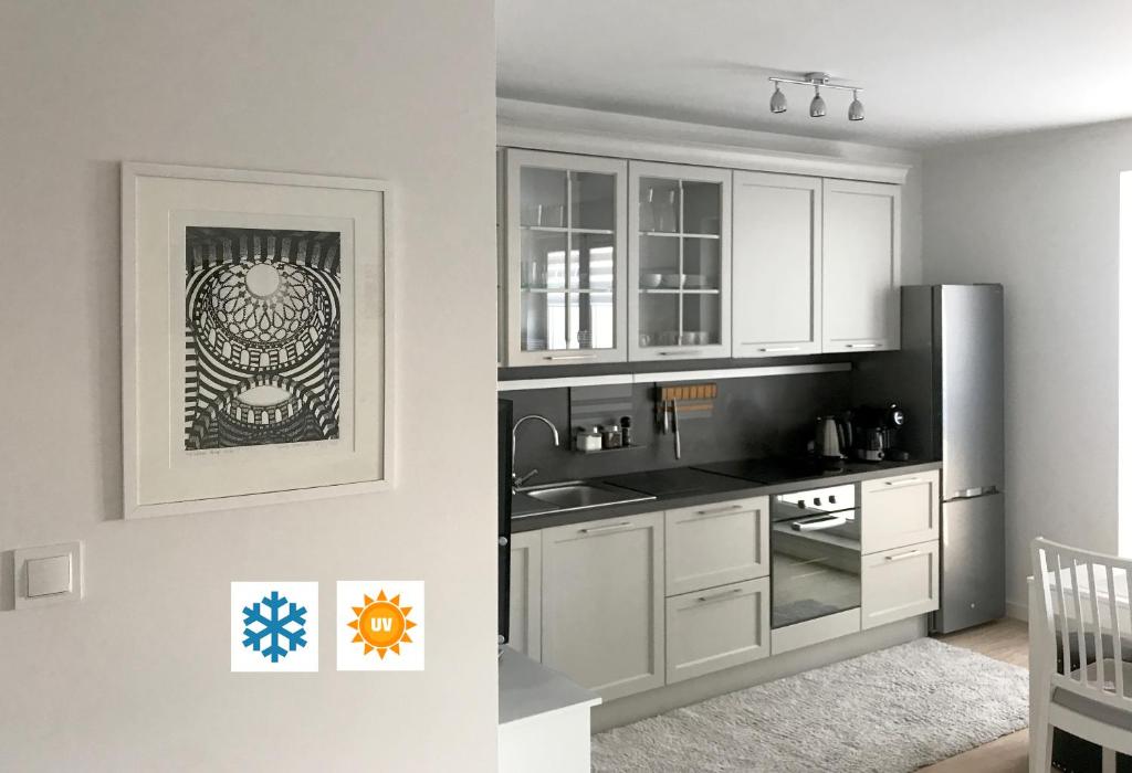 比亚韦斯托克Apartament Flora Deluxe Naświetlanie UV的厨房配有白色橱柜和不锈钢冰箱