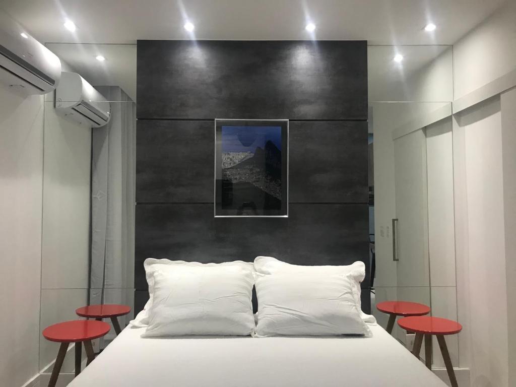 里约热内卢Ipanema Prudente Studio的卧室配有白色的床和红色凳子