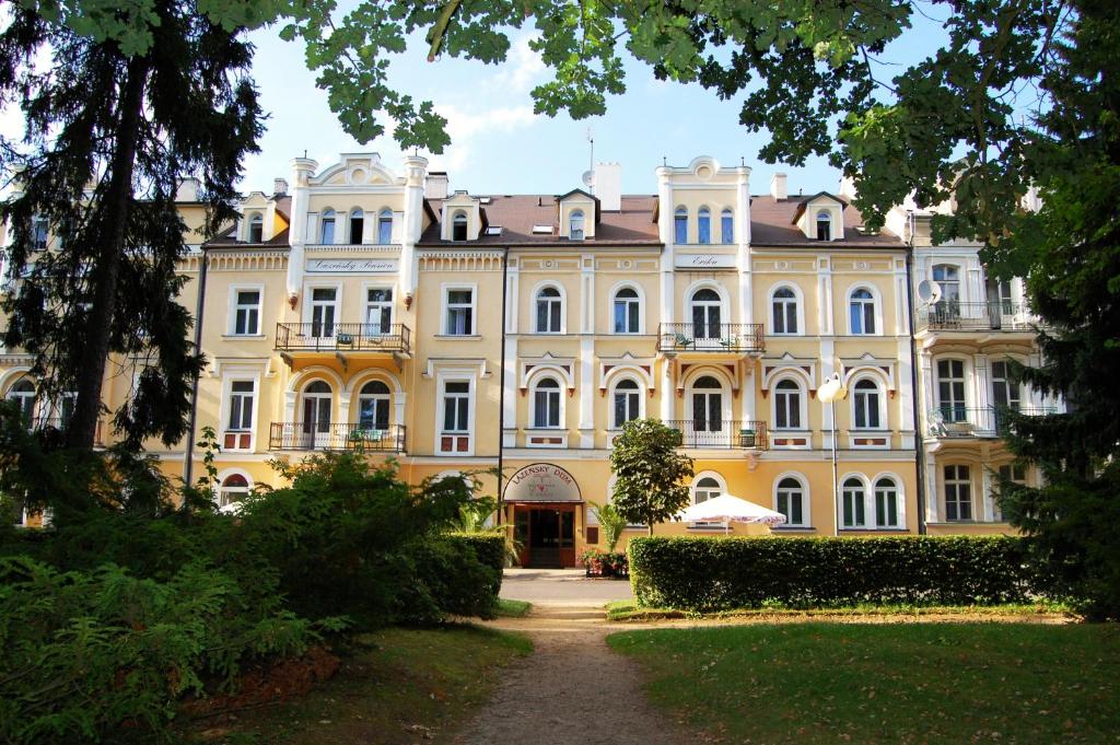 弗兰季谢克矿泉镇Lázeňský dům Erika的一座黄色的大建筑,前面有树木