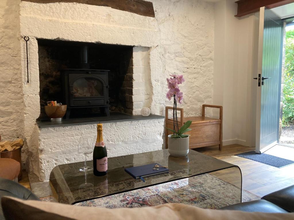 北贝里克Beautifully Renovated Self-Contained Farm Cottage - close to beaches, North Berwick and the Golf Coast的客厅设有壁炉,餐桌上备有一瓶葡萄酒