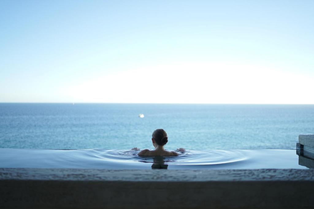 圣保罗湾城Mayflower Hotel Malta的坐在游泳池里,望着大海的人