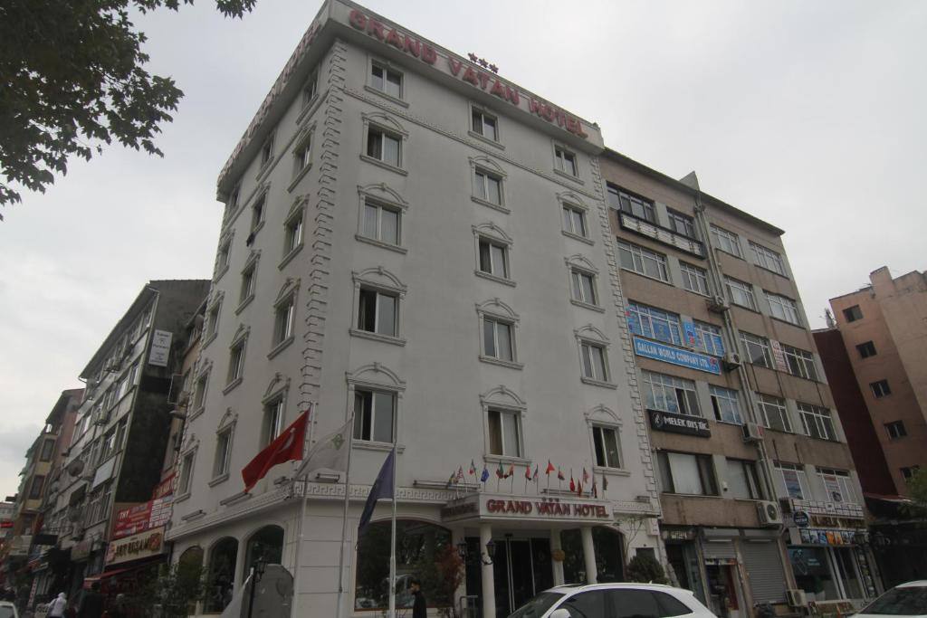 伊斯坦布尔GRAND VATAN HOTEL的城市街道上的白色建筑,有车