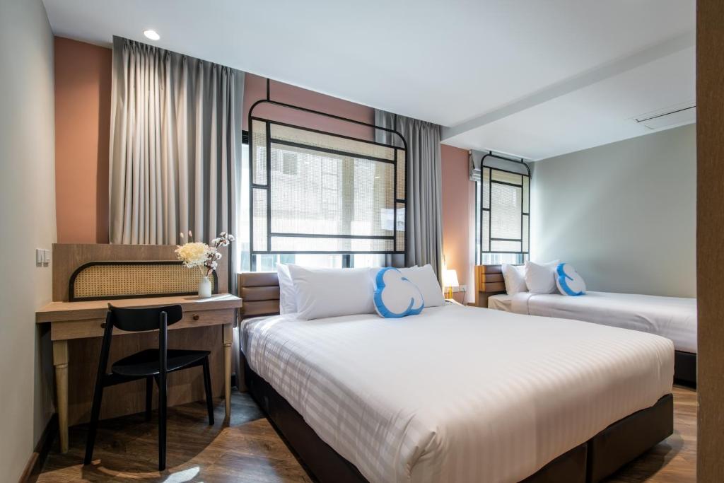 曼谷The Cotton Saladaeng Hotel的酒店客房配有两张床和一张桌子及椅子