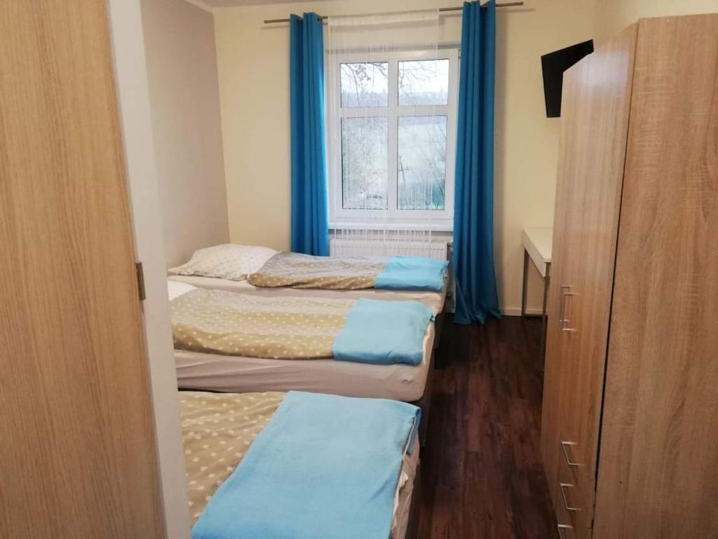 缅济莱谢Willa Wiktoria的客房设有三张床和一扇带蓝色窗帘的窗户。