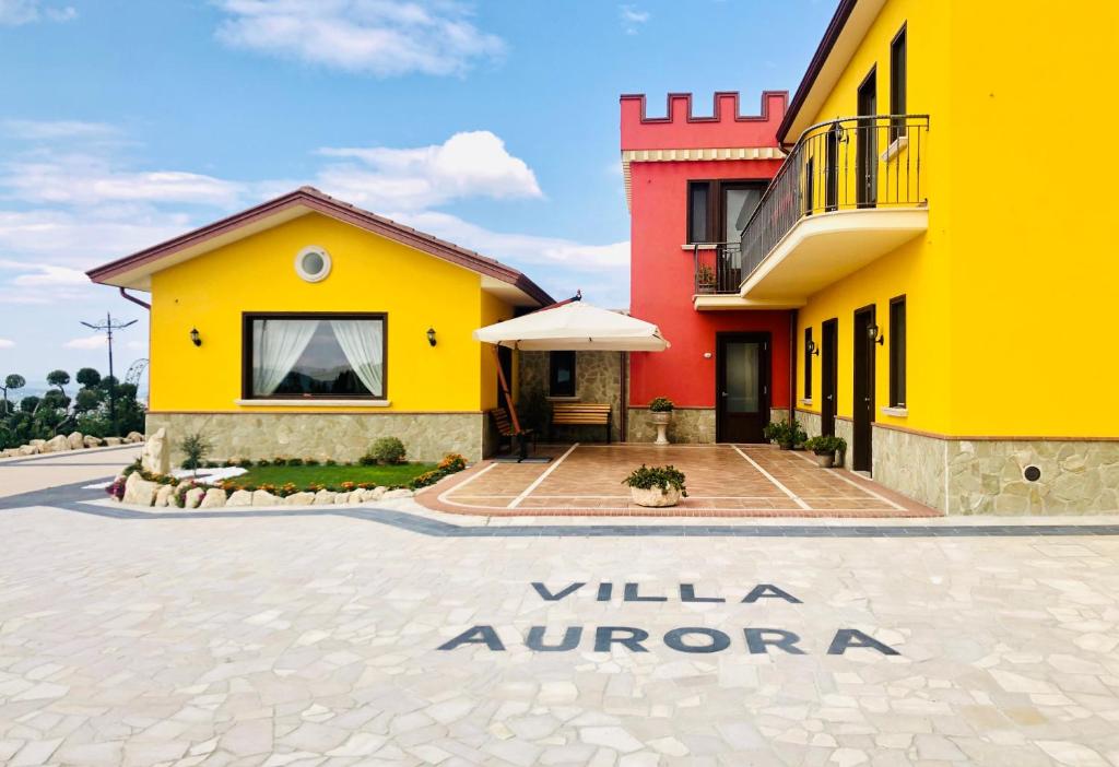 Villanova del BattistaVilla Aurora的黄色和红色的建筑,上面有读出灰柳的标志