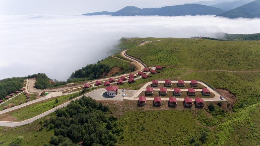 里泽Flora Handüzü Resort Bungalow的云中山丘上房屋的空中景观