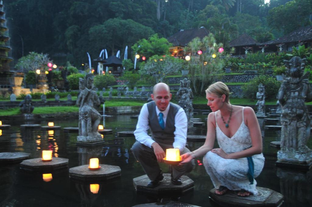 Tirtagangga提塔阿玉酒店及餐厅的把蜡烛放在花园中的男人和女人
