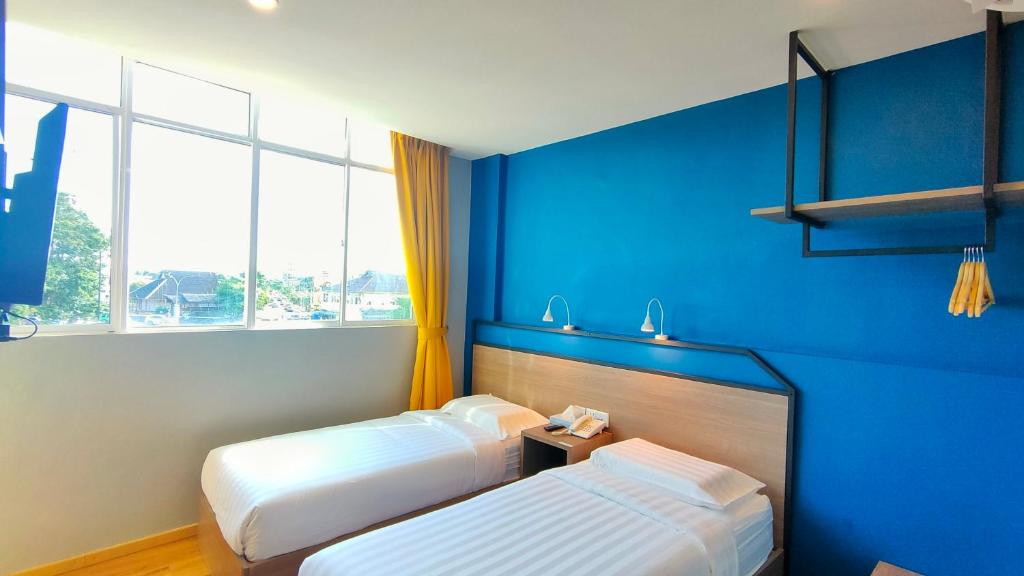 仙本那Uptown Hotel的蓝色墙壁客房的两张床
