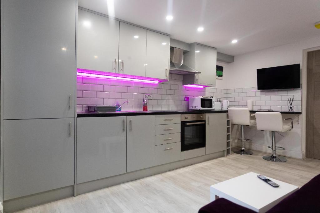 利兹Westwood Apartment的厨房配有白色橱柜和紫色灯