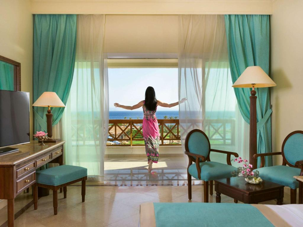 塔巴Movenpick Taba Resort & Spa的站在酒店房间,望向窗外的女人