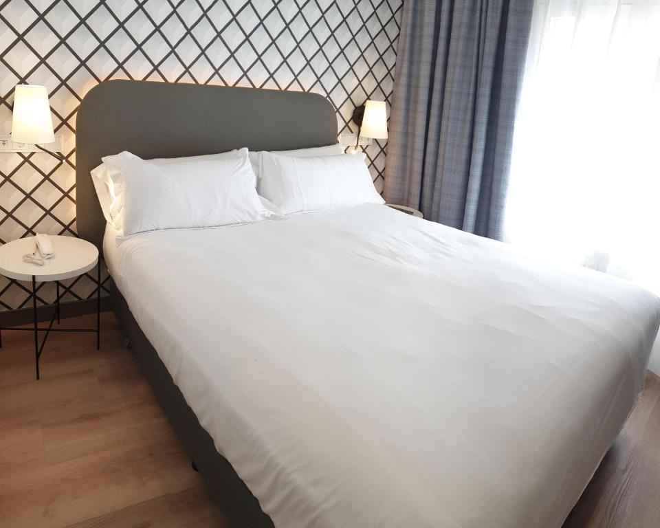 布尔戈斯雷斯雷耶斯卡多丽克斯酒店的一张带白色床单和枕头的床