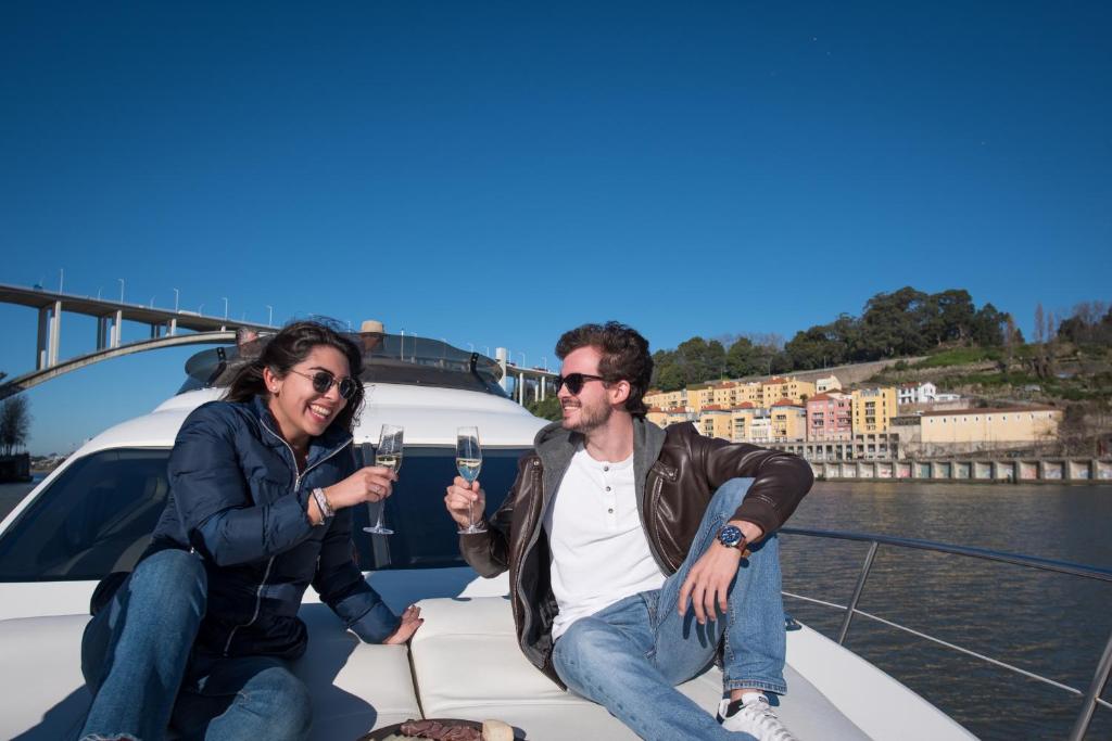 加亚新城Sailing 360 Night On Board Experience的坐在船上的男人和女人,拿着酒杯