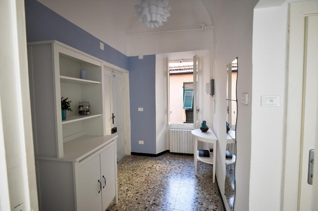 诺利La Zuacca, luminoso appartamento con terrazzo的厨房设有蓝色的墙壁、白色的橱柜和窗户。