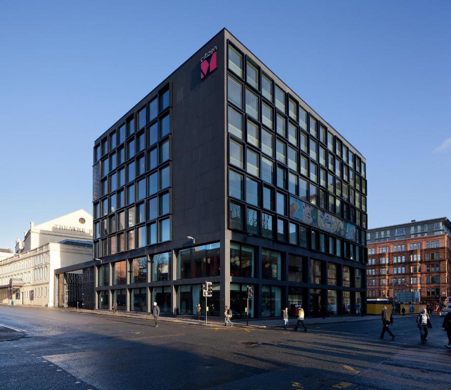 格拉斯哥格拉斯哥世民酒店的一座黑色的大建筑,旁边有一个标志