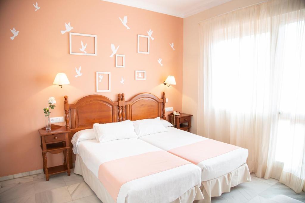 塞维利亚唐佩德罗宫酒店的卧室配有一张铺有白色床单的床,墙上有鸟儿
