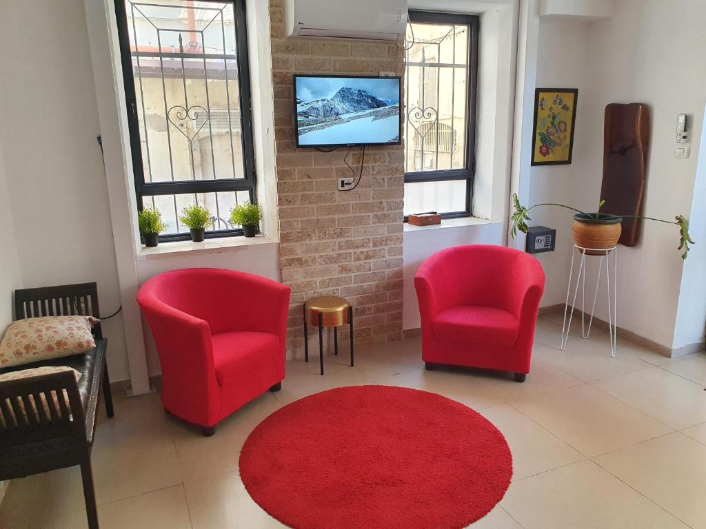海法BE ME Hotels and Hostels HAIFA ART的客厅配有两把椅子和红色地毯