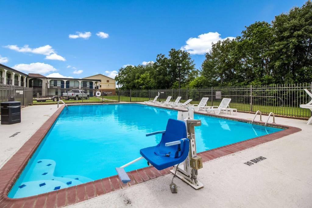 格罗夫斯Motel 6 Groves, Tx的一个带椅子和蓝色躺椅的游泳池