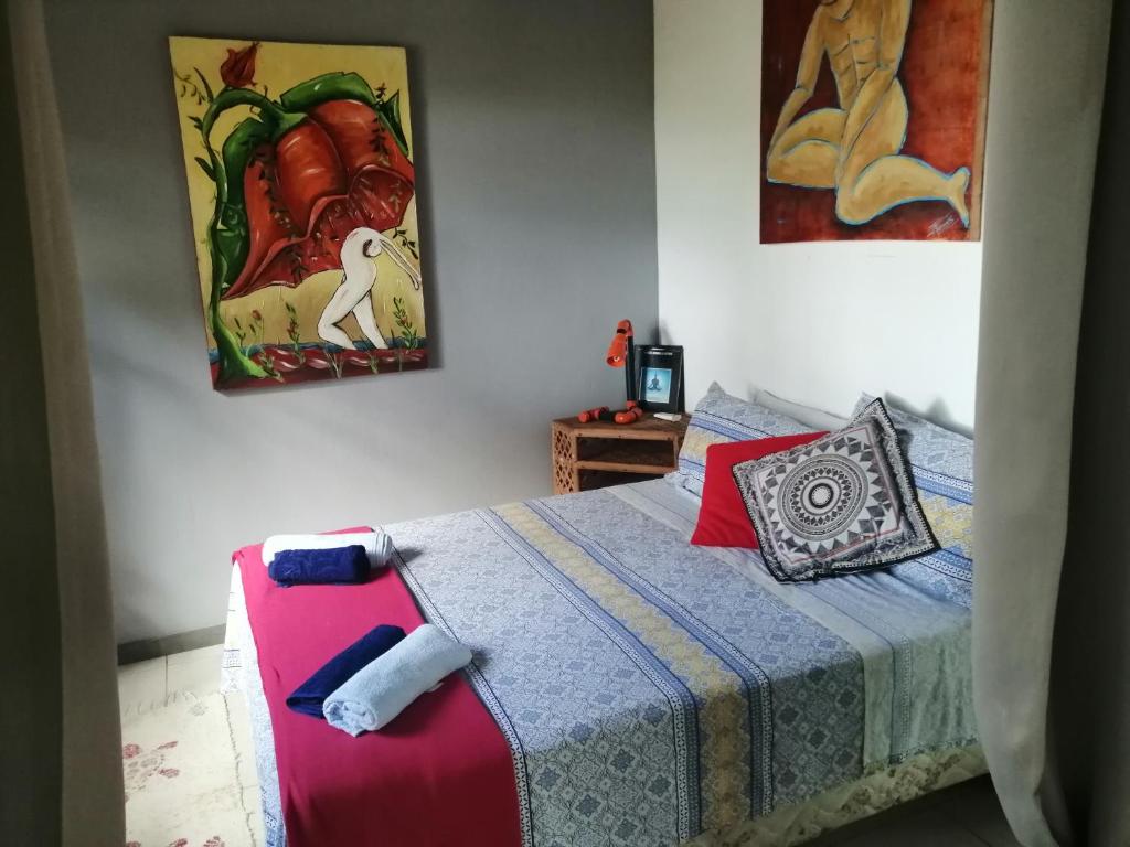 普拉亚多Chalé "Oasis"的卧室配有一张床,墙上挂有绘画作品