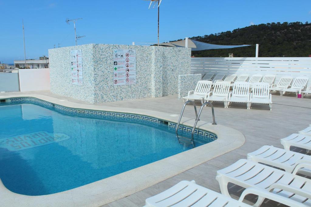 圣安东尼奥奥维公寓酒店的一座带白色椅子的游泳池,位于大楼旁