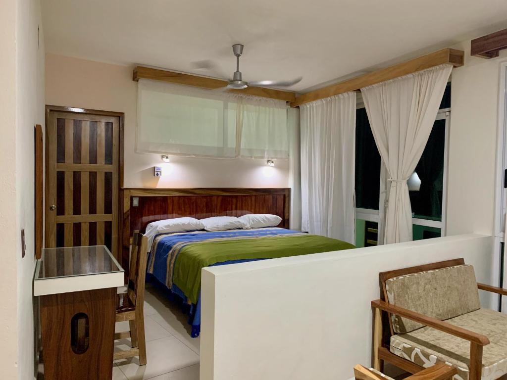 埃斯孔迪多港Lidxi Rosae的卧室配有1张床、1张桌子和1把椅子