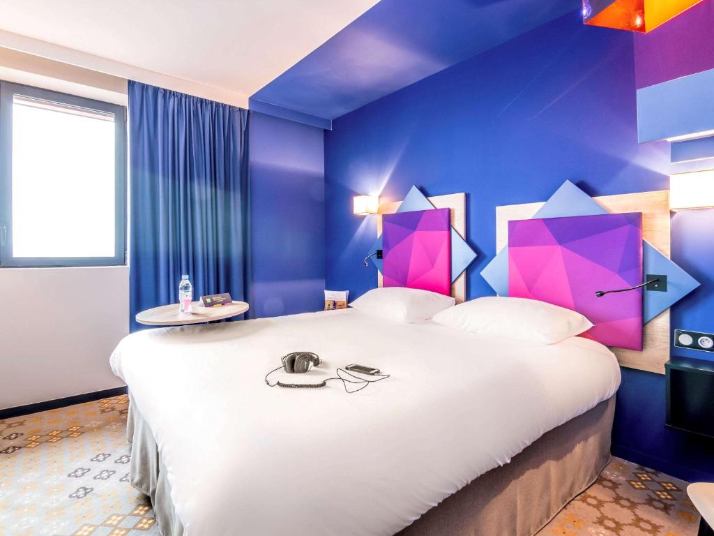 阿尔比ibis styles Albi Centre Le Theatro的卧室配有一张白色大床和紫色墙壁