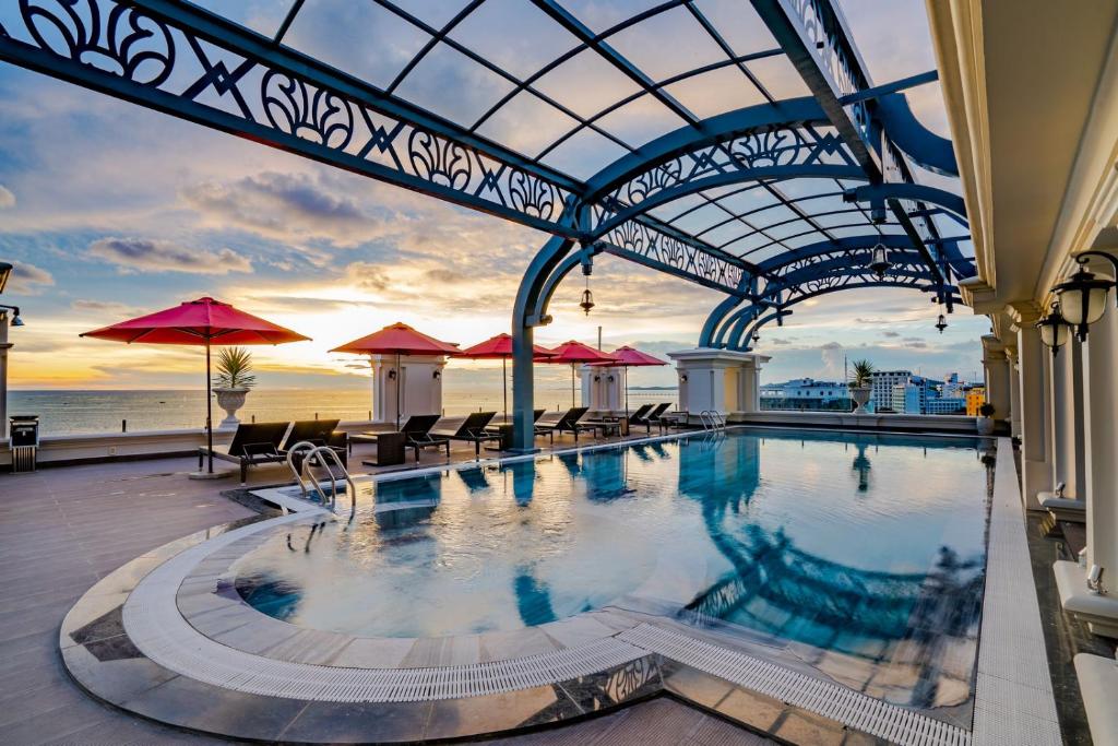 富国AVS Hotel Phu Quoc的大楼内带桌子和遮阳伞的游泳池