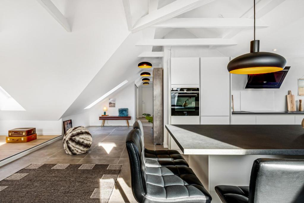 奥尔堡aday - Penthouse 3 bedroom - Heart of Aalborg的厨房以及带黑色椅子和柜台的起居室。