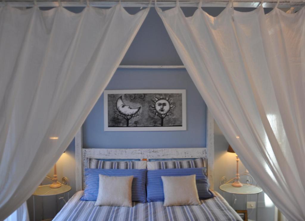 卡利亚里新罗曼蒂克公寓的卧室配有带白色窗帘的天蓬床