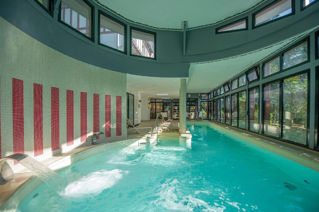 拉波勒Hôtel Miléade Les Pléïades La Baule的一座大型游泳池,位于一座带窗户的建筑内