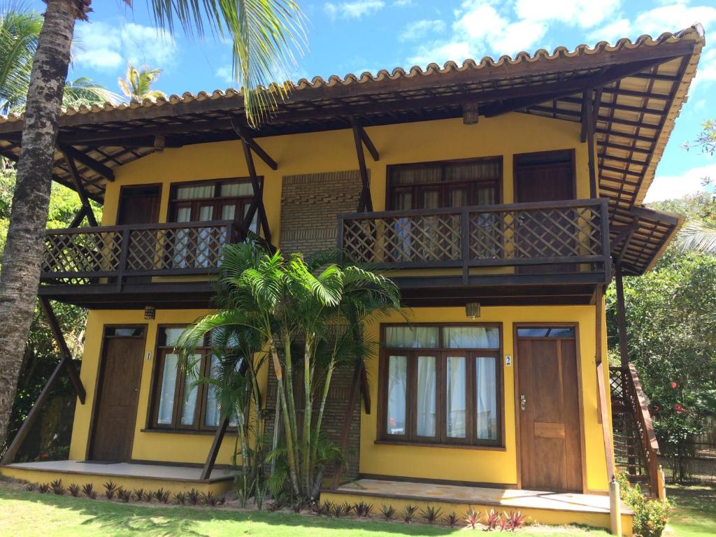 马劳Village em Taipu Fora - Apartamento pé na areia的黄色房屋,设有阳台和棕榈树