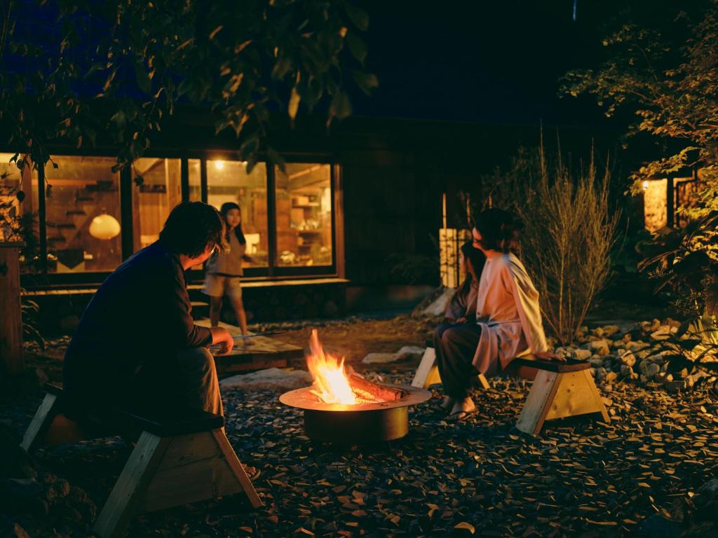 笛吹市古民家宿るうふ 澤之家的两人在晚上坐在火坑周围