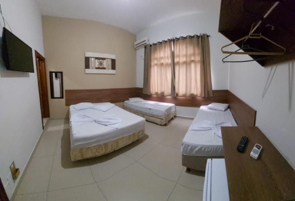 阿帕雷西达Suites Santa Terezinha的酒店客房设有两张床和一张桌子。