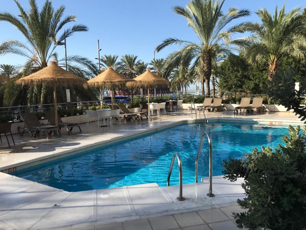 阿尔么丽亚Ohtels Gran Hotel Almeria的一个带桌椅的游泳池,棕榈树