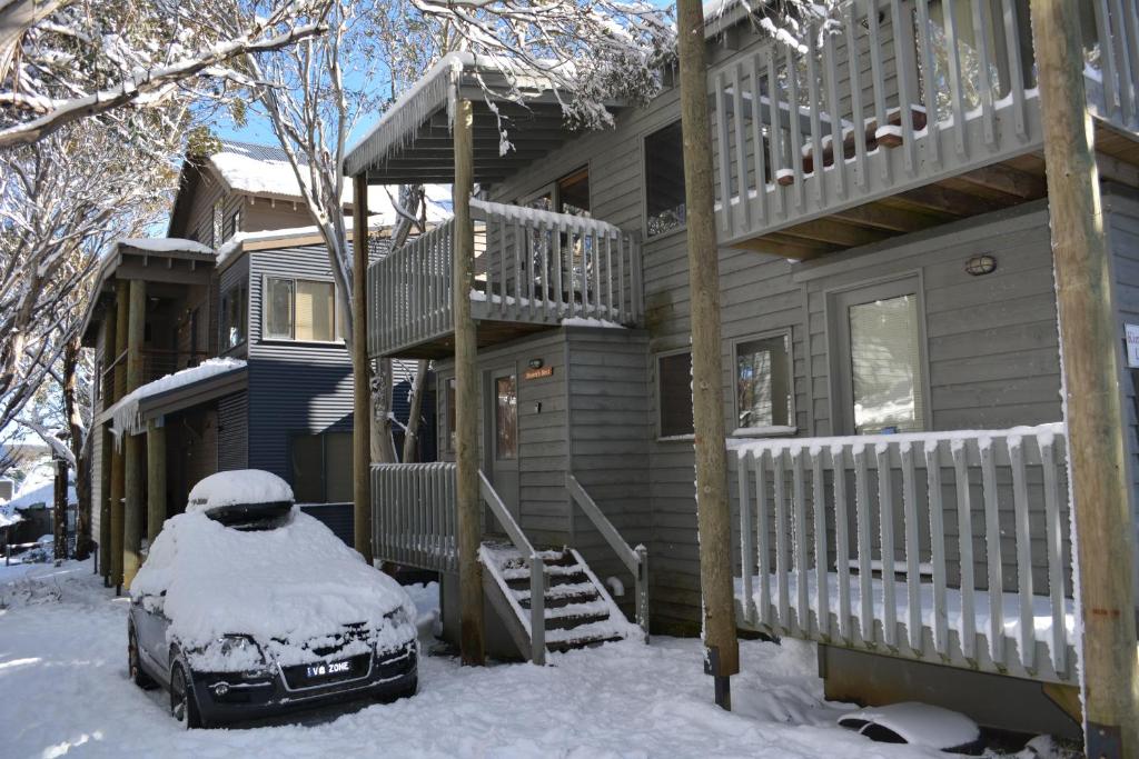 丁诺高原德罗维斯休闲度假屋的一座雪覆盖的房子,前面有一辆汽车停放