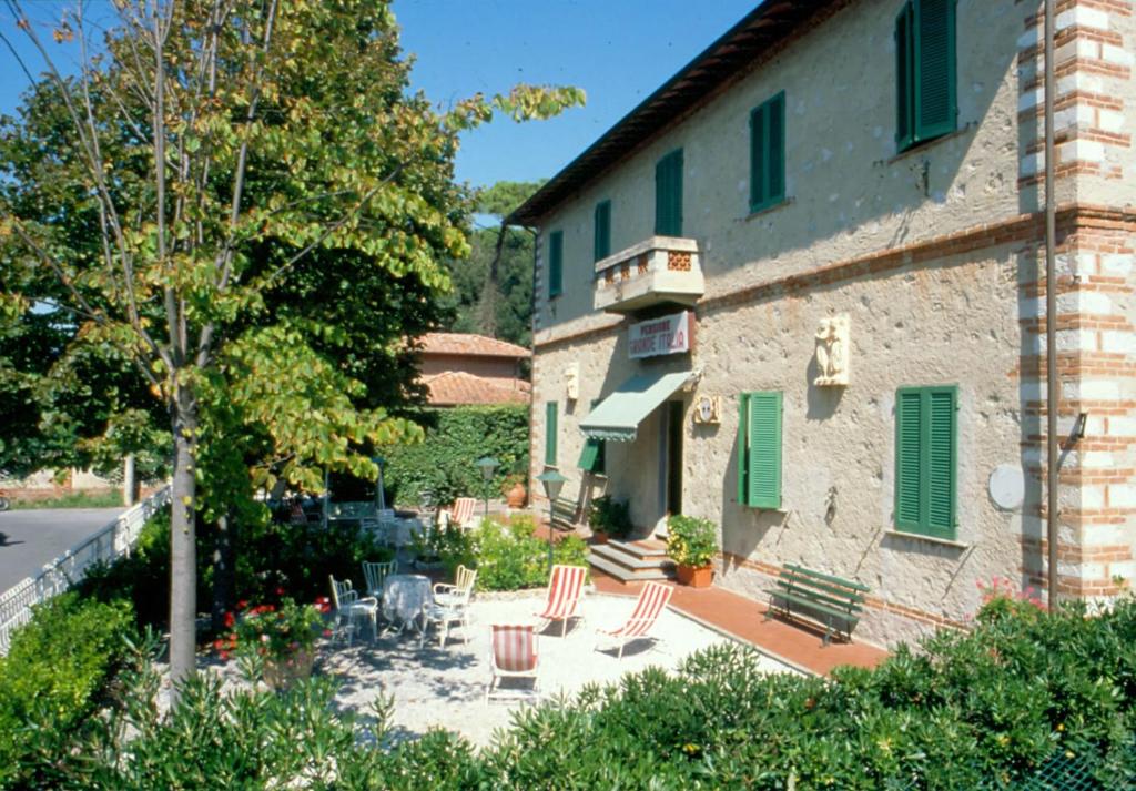 马里纳-迪-皮特拉桑塔Albergo Grande Italia的一座带椅子和树的露台的建筑
